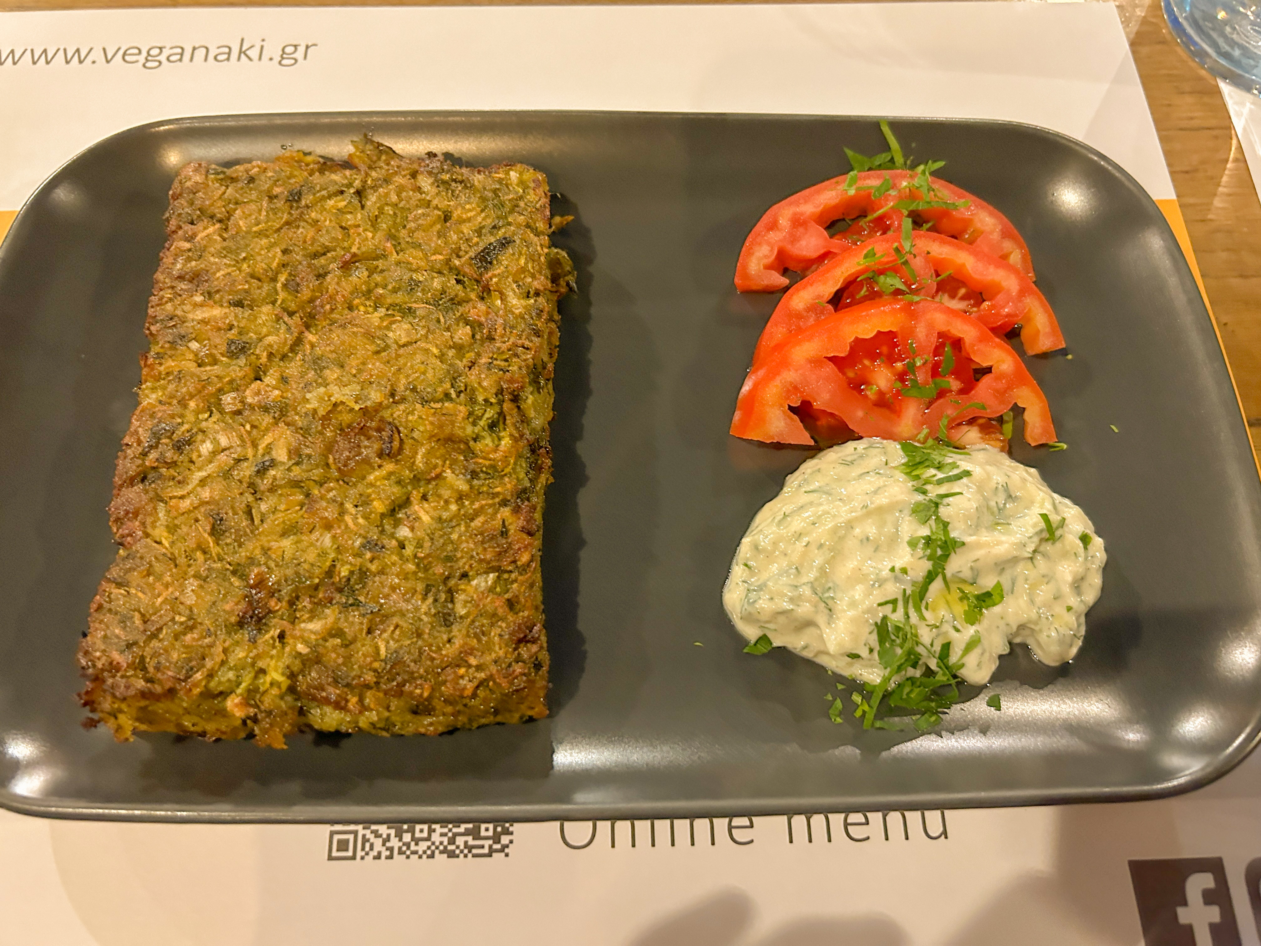 Rectangle shaped slice of crunchy zucchini dish. Tomatoes and sauce are placed neatly on the side.