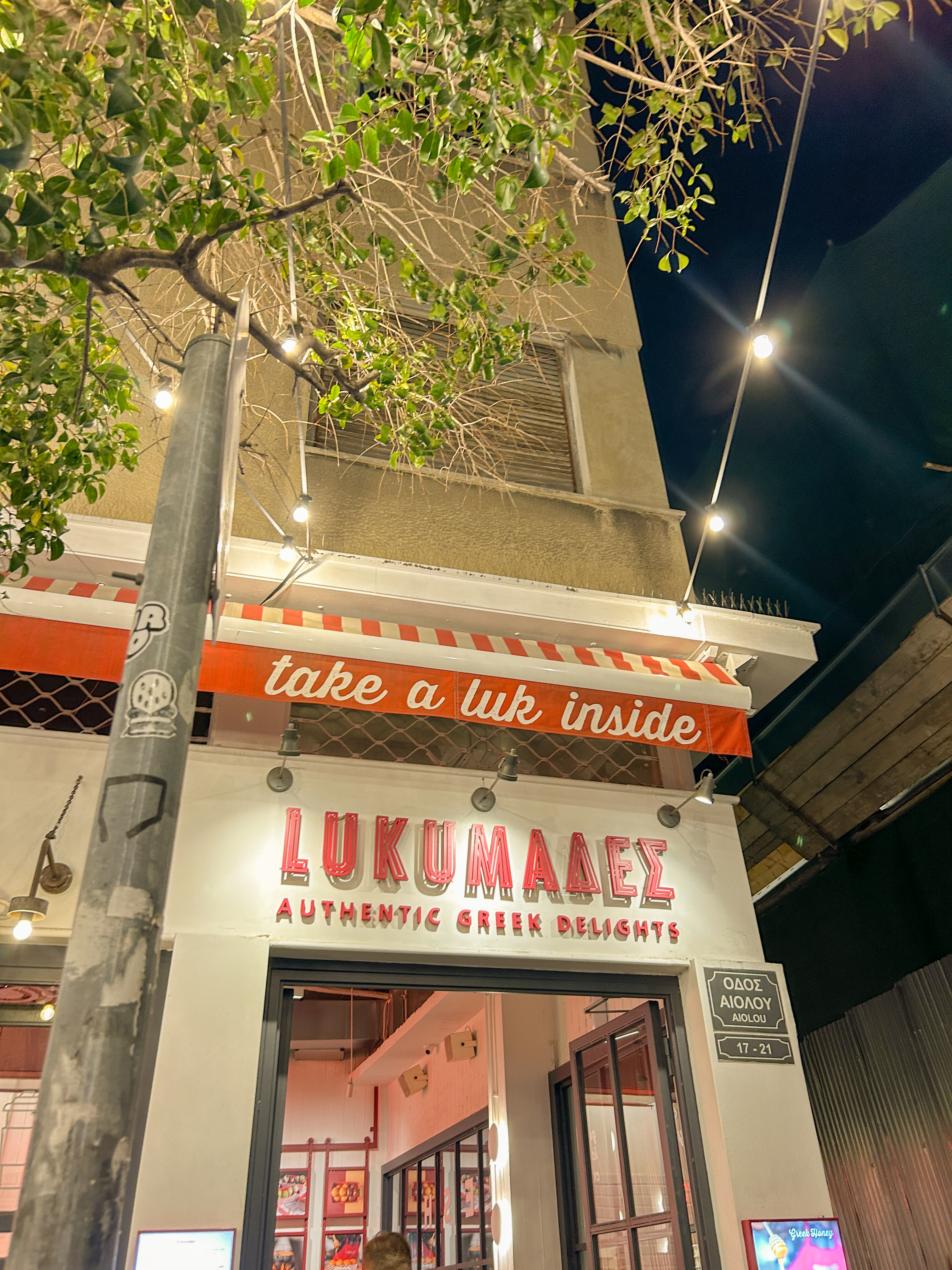 Exterior of Loukoumades restaurant. White building with red lettering.