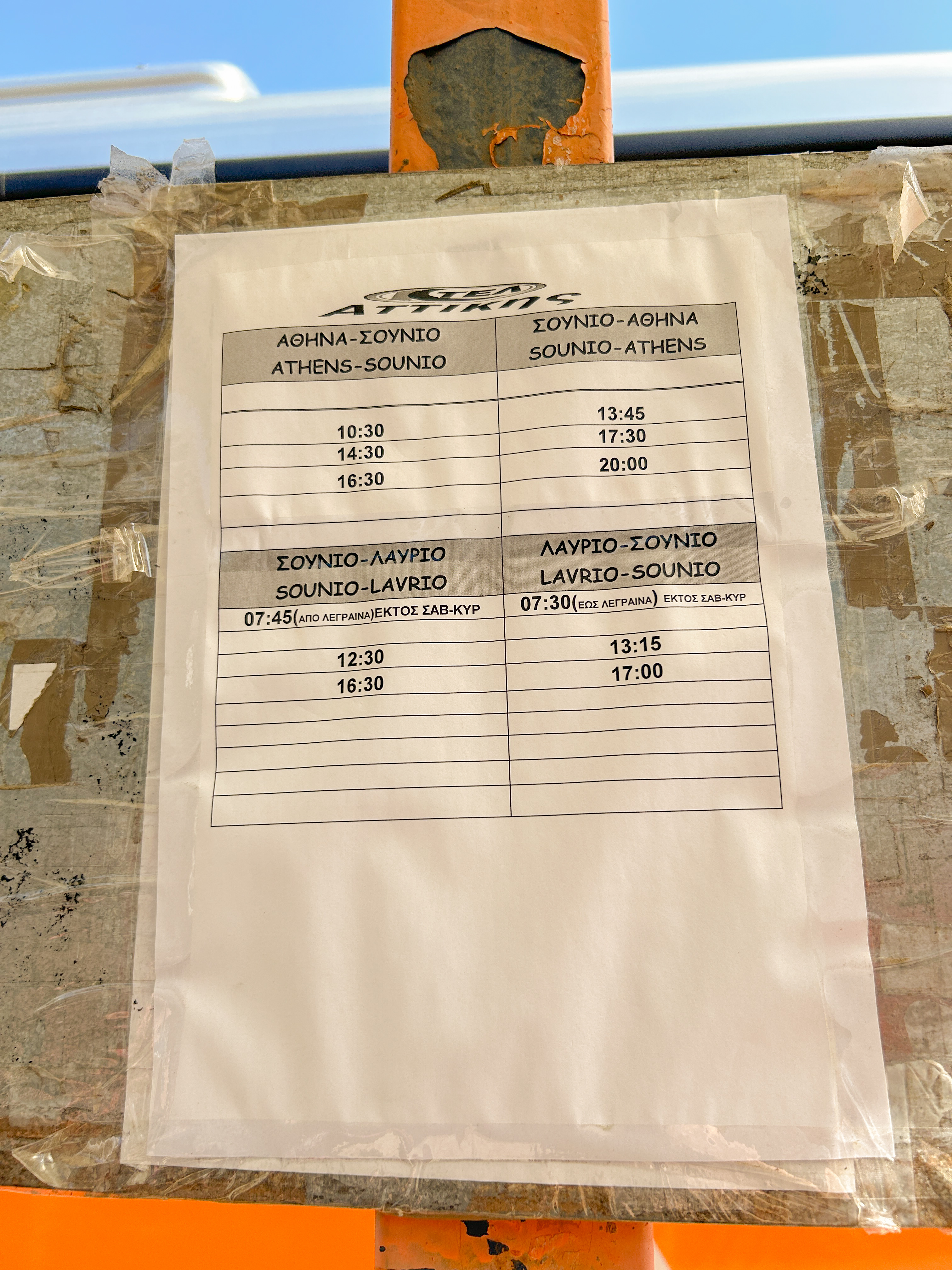 Piece of paper with the Athens to Sounion bus schedule. The paper is taped up at the bus station.
