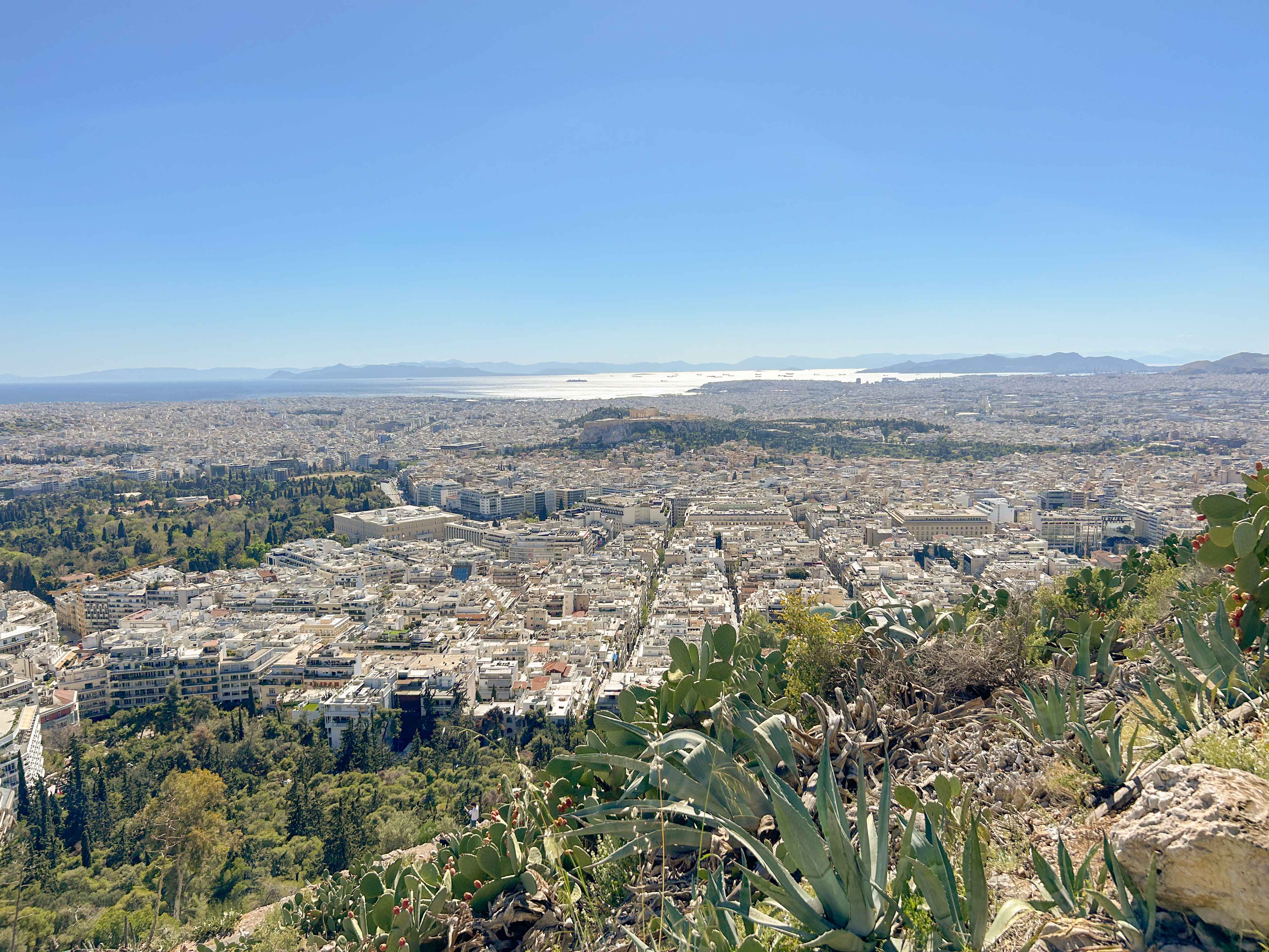 Viewpoint from the top of the mountain. Athens sprawls below a cloudless blue sky.